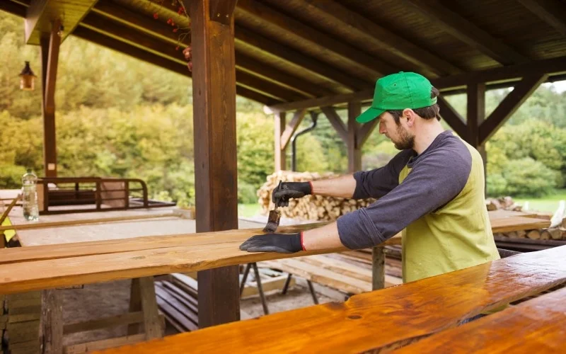 handyman-puts-varnish-on-wooden-planks-outside